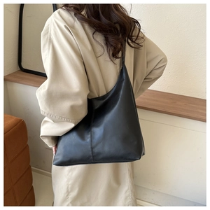 Rear view of model wearing a large matte black hobo tote bag with vertical stitching
