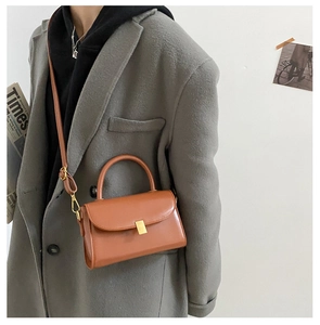 Close-up of caramel brown crossbody bag featuring a golden rectangular metal clasp and flap