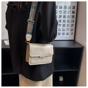Detail of beige retro square bag with adjustable vintage geometric patterned wide strap