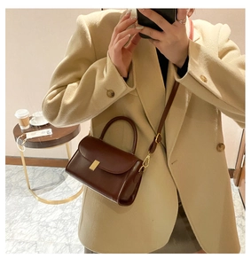Detail of vintage brown leather square bag with gold buckle on beige blazer