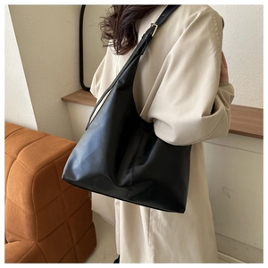 Detailed view of the black minimalist tote bag with golden buckle and wide shoulder strap
