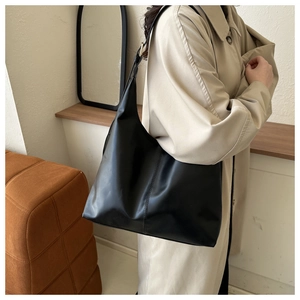 Chic black leather tote bag worn by a model in a natural setting for daily casual style