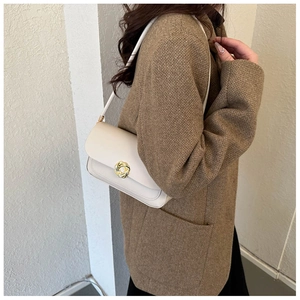 Close-up of cream leather shoulder bag featuring an elegant gold knot metal buckle