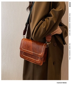 Close-up of brown retro oil-wax leather crossbody bag with wide canvas strap and stitching