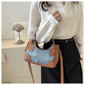 Detail of vintage patchwork shoulder bag with blue denim and brown leather contrast