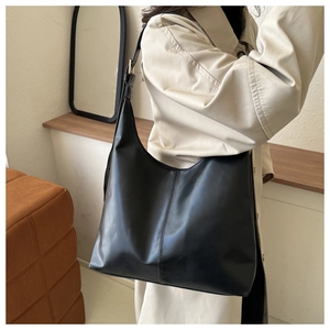 Detail of a sleek black PU leather hobo bag with adjustable strap on a female model
