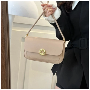 Detail of beige underarm bag showing the golden circular textured buckle and leather finish