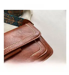 Detailed close-up of dark brown leather bag with beige stitching and woven wide strap