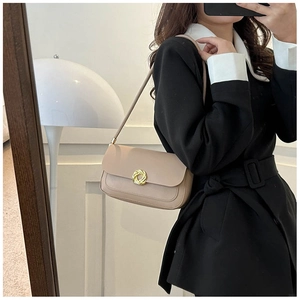 Detail of beige leather shoulder bag featuring a gold twisted metal buckle on the front flap