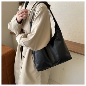 Detail of black faux leather tote bag with smooth texture and adjustable shoulder strap