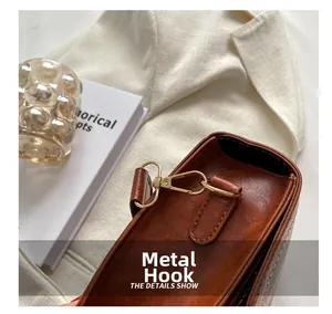 Close-up of golden hardware hook and stitching on dark brown vintage leather bag