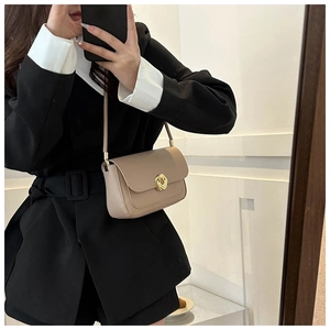 Detail of beige shoulder bag with a gold braided knot buckle shown in a mirror selfie