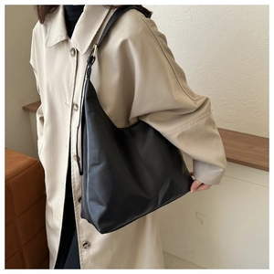 Detailed side view of a large black leather hobo tote bag worn by a model