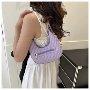 Detailed view of purple woven crescent shoulder bag with front zipper on female model