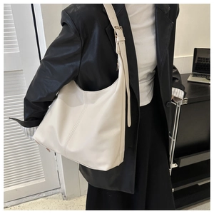 Detail of a creamy white soft leather tote bag showing the texture and adjustable strap
