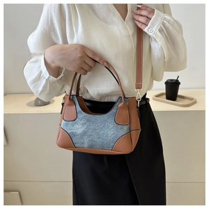 Detail of vintage contrast patchwork shoulder bag in denim and brown leather on a model