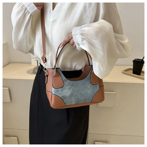 Detail of color-block underarm bag featuring brown leather and blue denim patchwork