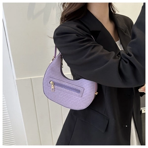 Detail of purple crescent shoulder bag with woven texture and gold zipper hardware