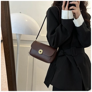 Detail of dark brown leather underarm bag with gold twisted metal buckle for women