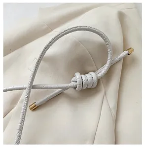 Detail of white textured strap with elegant gold hardware for minimalist crossbody bag
