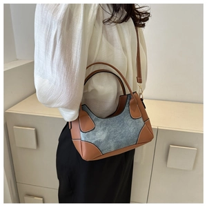 Detail of color-block contrast shoulder bag with brown leather and blue denim stitching