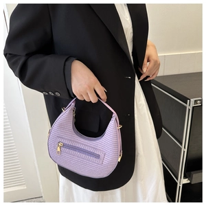 Detail of light purple woven crescent bag with gold zipper and textured finish