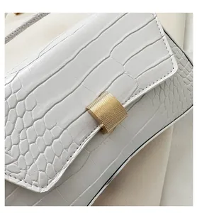 Detail of white crocodile texture faux leather bag with brushed gold metal buckle