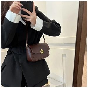 Detail of dark brown leather crossbody bag with vintage golden round metal buckle