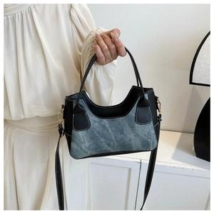 Detailed shot of a denim and leather patchwork crossbody bag with metallic gold hardware