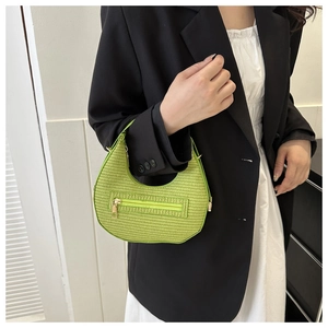 Close-up of grass green woven crescent bag with detailed texture and silver zipper