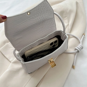Interior detail of white crocodile embossed crossbody bag with phone and sunglasses