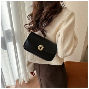 Detail of minimalist black rectangle shoulder bag with gold spiral twist lock on white tweed
