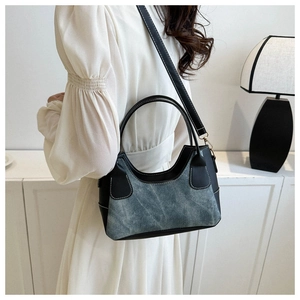 Detail of color-block baguette bag with blue denim and black faux leather contrast