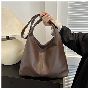 Detail view of large dark brown tote bag with wide shoulder strap and vertical stitching