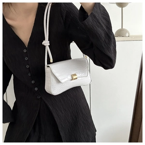 Close-up of white crocodile pattern shoulder bag with a gold metal square lock detail
