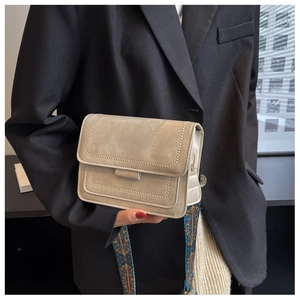 Detail of beige leather crossbody bag with vintage ethnic woven wide shoulder strap