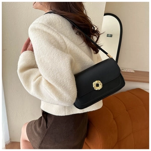 Model wearing a retro black leather crossbody bag with a gold ring clasp detail