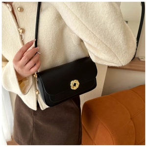 Detail of a vintage black leather underarm bag with a golden circular knot metal buckle