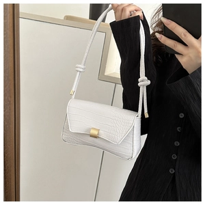 Close-up of white crocodile pattern shoulder bag with matte gold buckle and knot detail