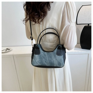 Detail of blue denim and black leather patchwork shoulder bag styled with elegant minimalist attire