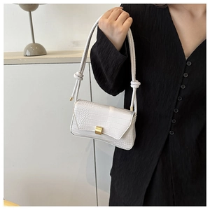 Detail of white crocodile embossed shoulder bag with gold square buckle and knot strap