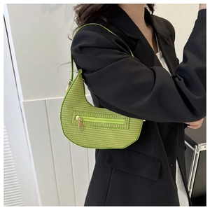 Detail of green crescent shoulder bag with woven texture and gold zipper accents