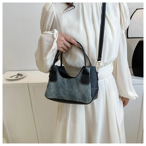 Detail of color-block mini handbag featuring blue textured fabric and black leather handles