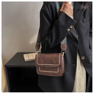 Vintage brown leather crossbody bag with ethnic woven strap shown on a black blazer