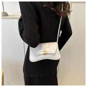 Detail of white crocodile embossed shoulder bag with gold clasp shown on a model back