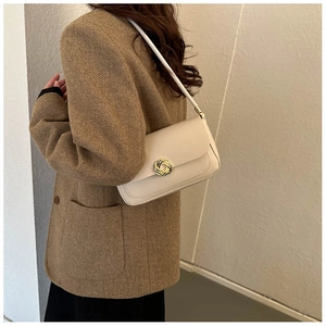 Detail of off-white shoulder bag featuring a gold twisted round clasp on a flap closure