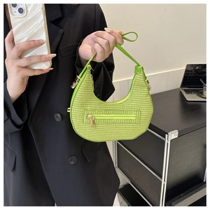 Detail showing fluorescent green woven texture and golden zipper on the crescent handbag