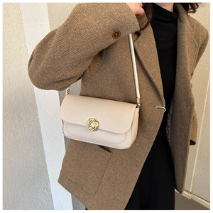 Minimalist beige crossbody square bag with gold knot buckle on model in brown blazer