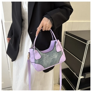 Detail of lavender and grey patchwork shoulder bag with gold hardware on a model