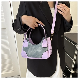 Detail of minimalist contrast stitching underarm bag with purple leather and denim patchwork